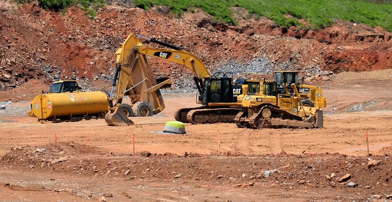 Excavator and bulldozer working on a large cleared dirt site